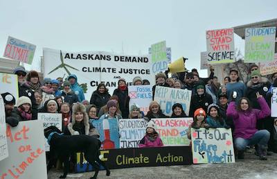 Large group of activists of all ages in winter gear holding pro-science, pro-climate action signs